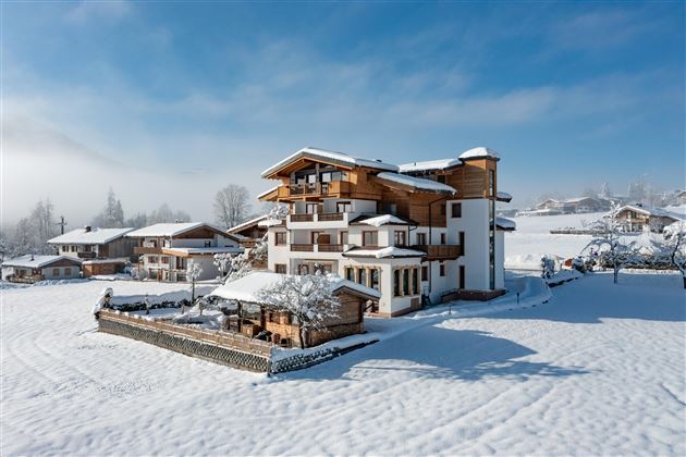 Ein wunderschönes, modernes Haus im Schnee. Die Umgebung ist malerisch und von schneebedeckten Bäumen umgeben.