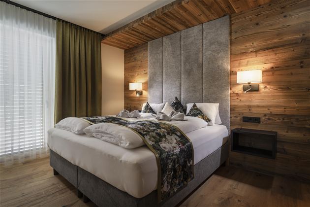A cozy bedroom with a large bed, modern design, and wooden walls.  
Large windows let in plenty of light and create an inviting atmosphere.