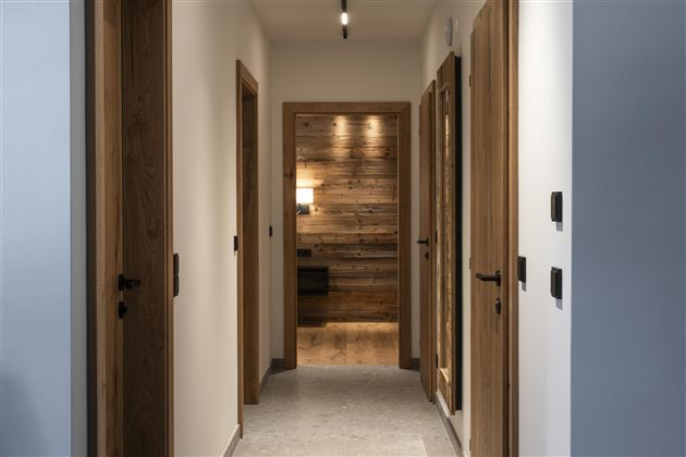 A modern corridor with wooden and white walls. Doors on both sides lead to different rooms.