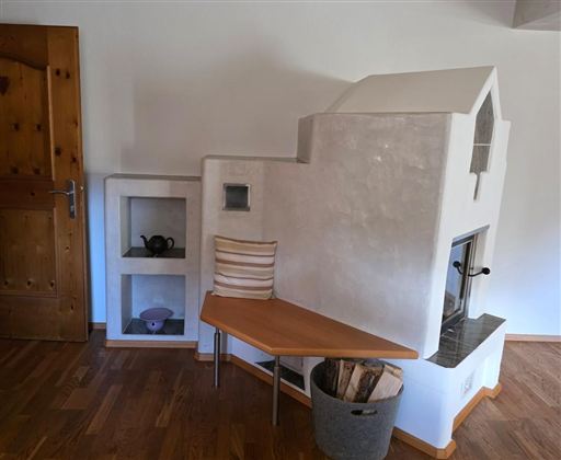 Een moderne haard met een eenvoudig ontwerp in een gezellige ruimte. Daarnaast is er een houten plank en een plek voor decoratie.