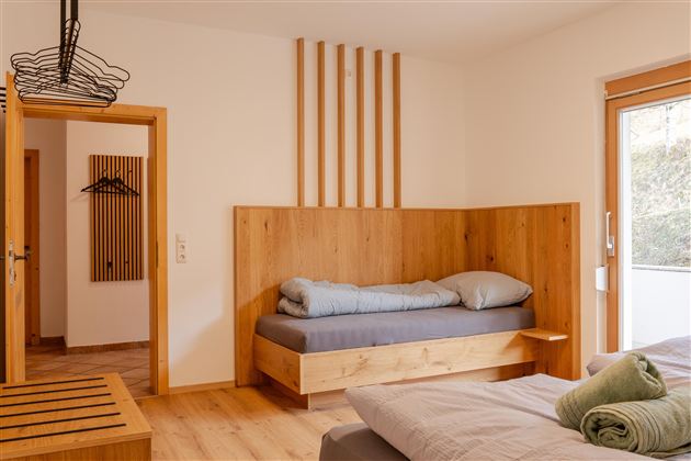 Een moderne kamer met houten details en twee bedden. Grote ramen zorgen voor veel natuurlijk licht.
