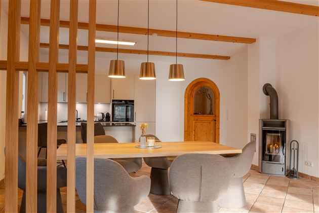 Een moderne keuken met een eetgedeelte en stijlvolle stoelen. In de hoek staat een gezellige open haard.