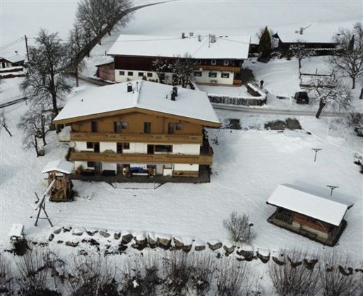 A cozy wooden house in a snowy landscape. Surrounded by snow-covered trees and a peaceful winter environment.