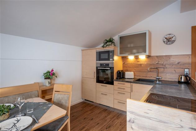 Eine moderne Küche mit Holz- und Metalloberflächen. Der Essbereich ist gemütlich gestaltet und bietet Platz für mehrere Personen.