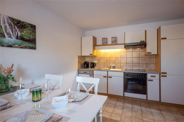 Eine moderne Küche mit hellen Schränken und einem Essbereich. Die Atmosphäre ist einladend und gemütlich.