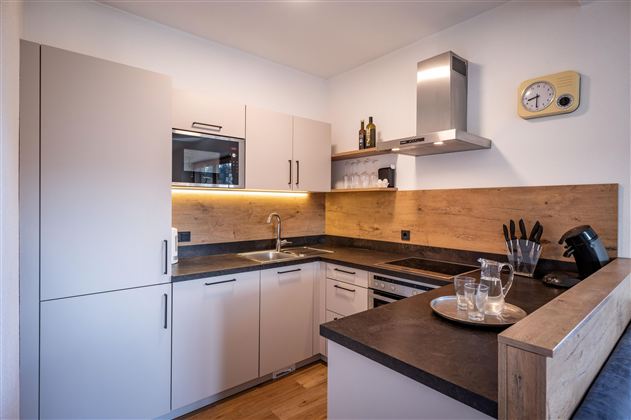 A modern kitchen with bright cabinets and wood accents. It features a sink, a stove, and dishes on the countertop.