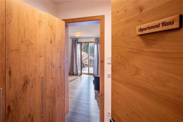 An inviting hallway with wooden panels that leads to a cozy apartment. A sign reads "Apartment Hans".
