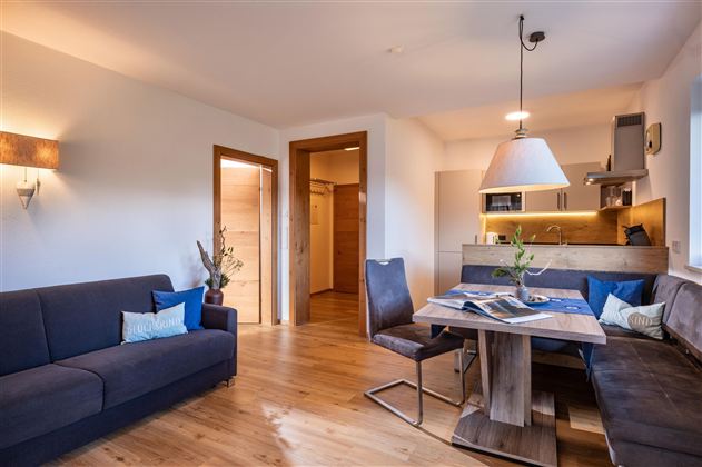 A modern living room with a cozy couch and a dining table. The bright, inviting atmosphere is highlighted by the wood design and the lighting.