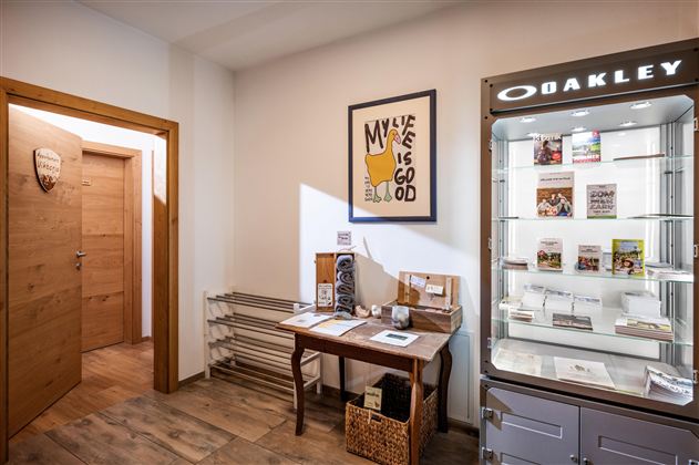 An inviting room with wooden walls and a table. A display case showcases products and magazines, while a piece of art hangs on the wall.