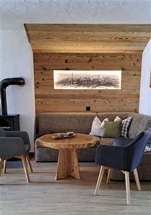 Ein gemütlicher Wohnbereich mit modernen Möbeln und einer Holzverkleidung. Der runde Tisch aus Holz ergänzt die entspannte Atmosphäre.