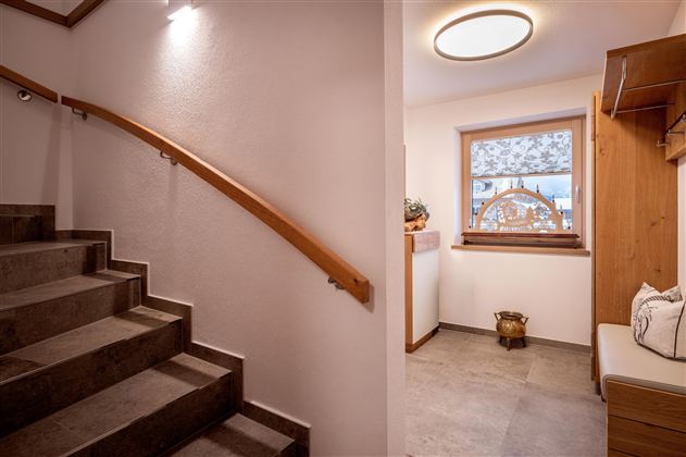 Een uitnodigende gang met een trap en een helder raam. De inrichting is modern en gezellig.