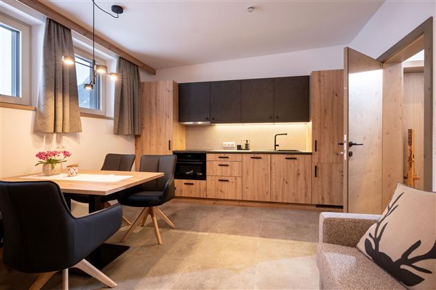 Een moderne keuken met houten oppervlakken en een eettafel in een lichte ruimte. De ruimte heeft grote ramen en een uitnodigende sfeer.