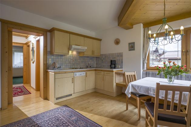 A bright kitchen with modern wooden design and a dining table. There is a beautiful bouquet of flowers on the table and a cozy atmosphere.