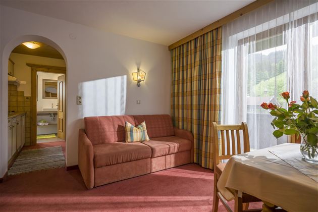 A cozy living room with a sofa and a dining area. The windows let in plenty of light and offer a view of the surroundings.
