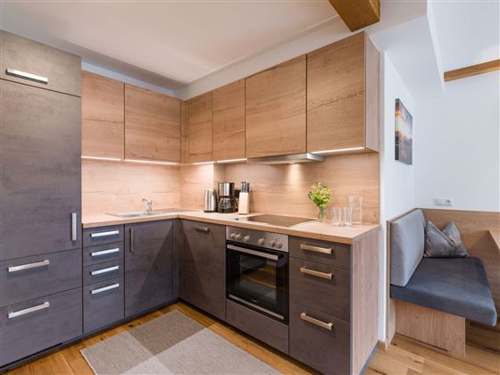 Eine moderne Küche mit Holz- und Metallelementen. Sie ist gut ausgestattet mit einem Herd, einer Spüle und einer gemütlichen Sitzecke.