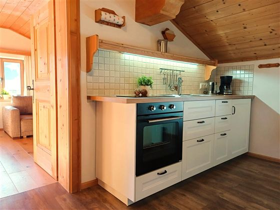 Een moderne keuken met een witte keukenlijn en een zwarte fornuis. De houtdecoratie en de warme verlichting geven de keuken een gezellige sfeer.