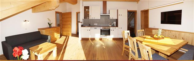 Eine helle und moderne Wohnung mit Holzverkleidung. Sie verfügt über eine offene Küche, einen Essbereich und komfortable Möbel.