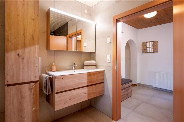 Ein modernes Badezimmer mit Holzregalen und einem eleganten Waschbecken. Die warmen Farben und das klare Design schaffen eine angenehme Atmosphäre.