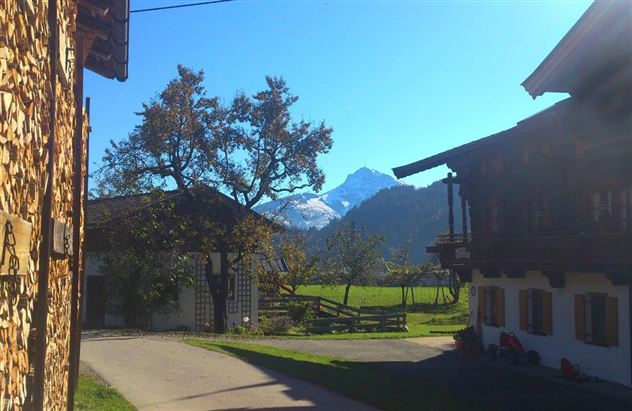 Een schilderachtig landschap met bergen op de achtergrond. Op de voorgrond zijn traditionele huizen en bomen te zien.