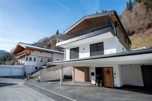 Ein modernes Haus in einer verschneiten Landschaft. Der Himmel ist grau und die Umgebung ist ruhig und winterlich.