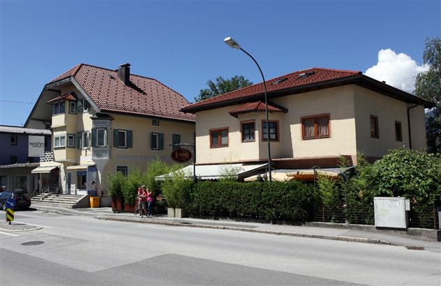 Twee traditionele gebouwen aan een straat in een rustige omgeving. De lucht is blauw met enkele wolken.