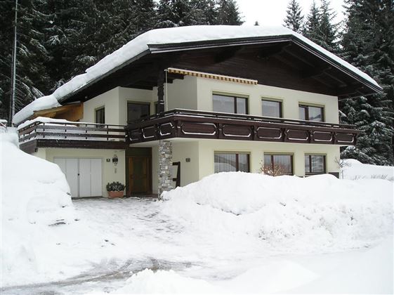 A charming house in the snow with a large balcony.  
Surrounded by snow-covered fir trees.