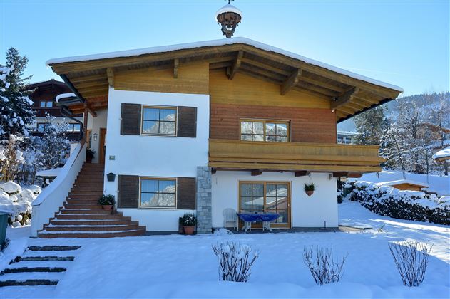 Ein schönes Haus im Alpenstil, umgeben von Schnee. Die klare Winterlandschaft verleiht der Szene eine gemütliche Atmosphäre.