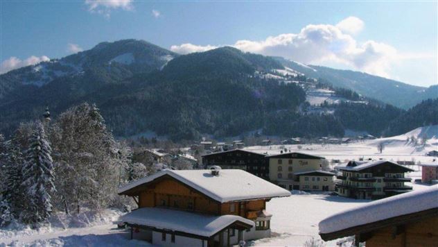A beautiful winter landscape with snow-covered mountains and charming cottages. The clear sky and the snow create a peaceful atmosphere.