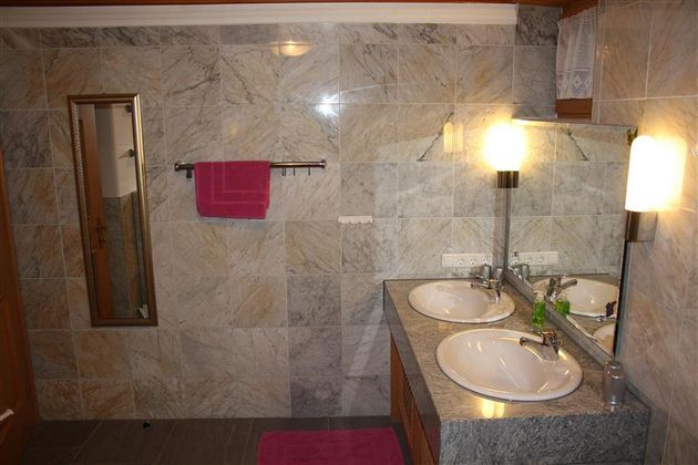 Ein modernes Badezimmer mit zwei Waschbecken und großem Spiegel, Badewanne, Dusche und WC