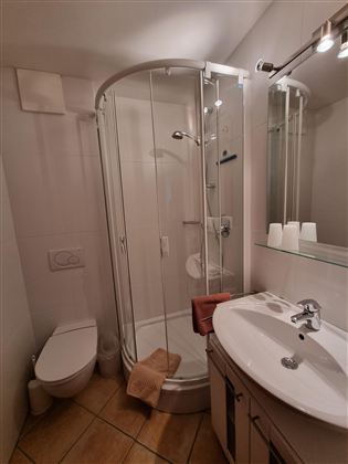 Een moderne badkamer met een douchecabine en een wastafel. Het ontwerp van de ruimte is licht en functioneel met een elegante afwerking.