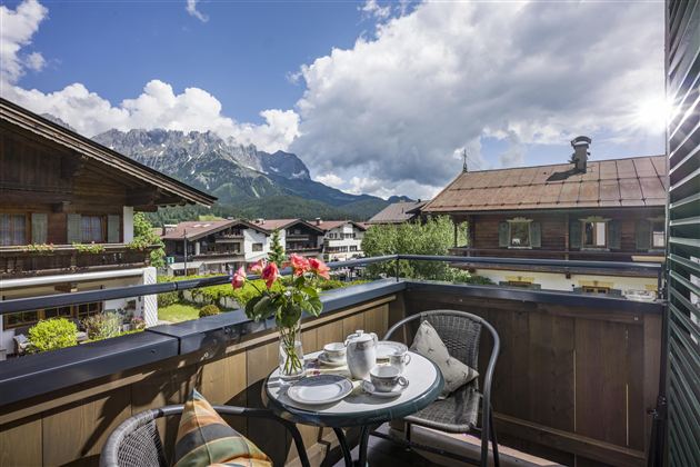 A cozy balcony overlooking the mountains. A table with a teapot and fresh flowers invites you to relax.