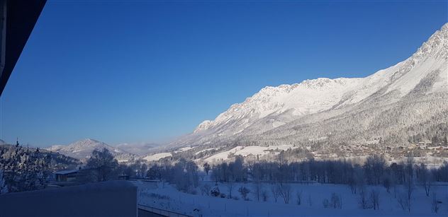 A snow-covered mountain landscape under a clear blue sky. The mountains are majestic and the scenery is calm and idyllic.
