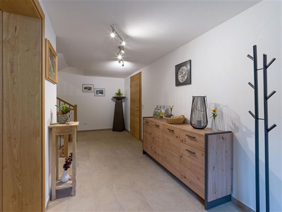 A modern hallway with wooden shelves and a stylish floor lamp. The walls are painted light and there are some decorative elements.