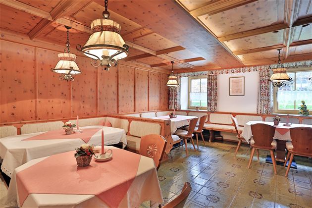 Een gezellig restaurant met houten panelen en warme verlichting. De tafels zijn netjes gedekt en nodigen uit om te blijven hangen.