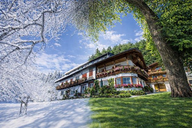 A picturesque building amidst a winter landscape. Snow covers the ground while the facade is decorated with colorful flowers.