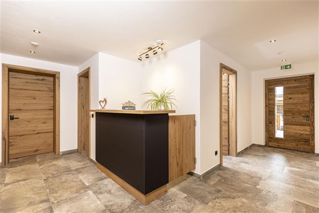 A modernly designed reception area with wooden and stone flooring. Several doors lead to different rooms.