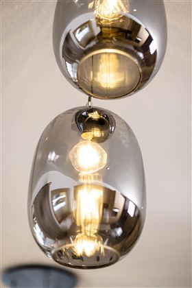 A modern pendant light with glass pendant housings. The light has warm illumination and reflects the surroundings.