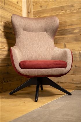 A modern, comfortable armchair with a gray and red cover. It stands in a wood-paneled room on a light floor.