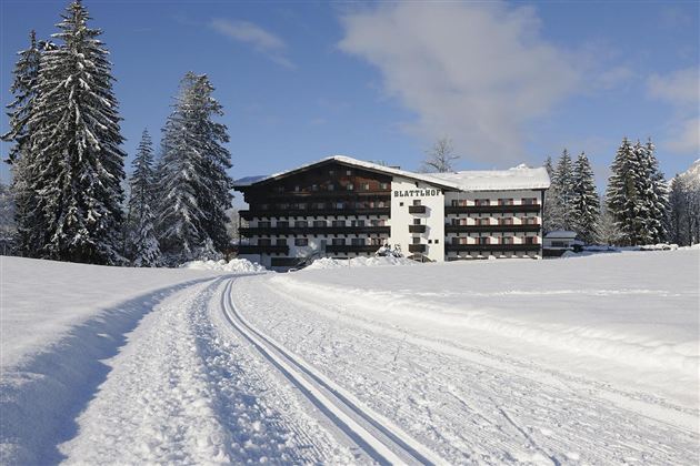Ein charmantes Hotel umgeben von verschneiten Bäumen. Eine gut präparierte Loipe führt direkt zum Gebäude.