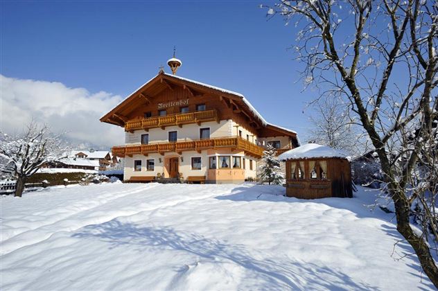A beautiful, snow-covered house with rustic balconies. Surrounded by snow-covered trees and a clear winter landscape.