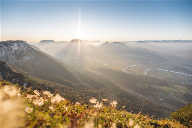 A stunning view of a mountain valley at sunrise. The gentle hills and the river in the valley are surrounded by fog.