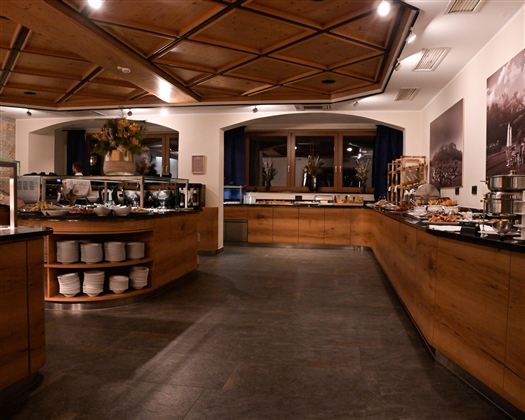 A modern restaurant with a wooden counter and a rich buffet. Soft lighting creates an inviting atmosphere.