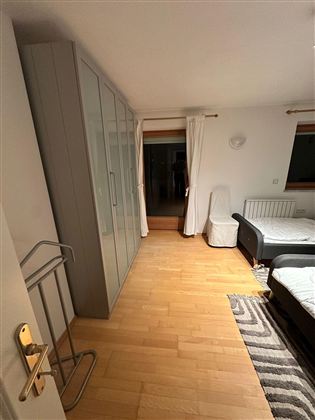Ein einfaches Schlafzimmer mit einem großen Kleiderschrank und zwei Betten. Der Boden ist aus hellem Holz und die Wände sind neutral gestrichen.