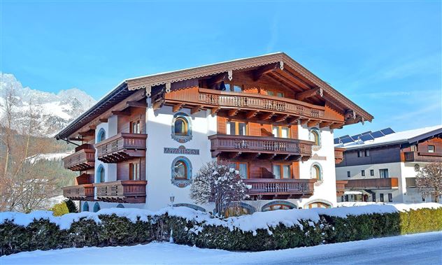 A beautiful chalet covered in snow in winter. The architecture is traditional and inviting.