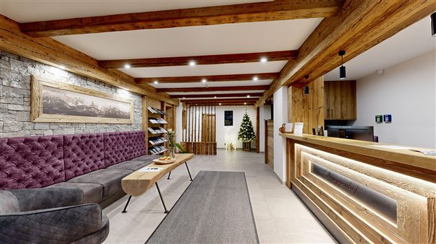 A stylish reception area with wooden beams and a cozy sofa. A small Christmas tree and warm light accents create an inviting atmosphere.