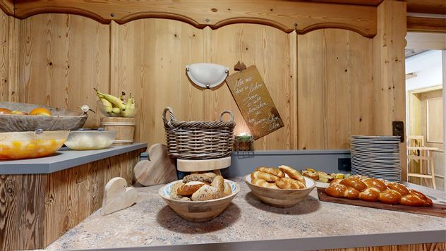 A cozy breakfast area with fresh fruit and various rolls. The wooden paneling creates an inviting atmosphere.