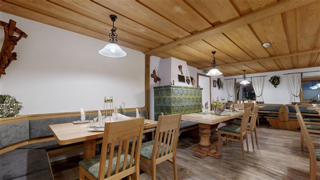 A cozy restaurant with wooden furniture and warm lighting. Tables are set for guests to create an inviting atmosphere.