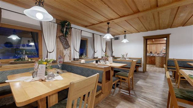 A cozy restaurant with wood interiors and light wooden tables. The atmosphere is inviting and rustic, with beautiful decorations and plants.