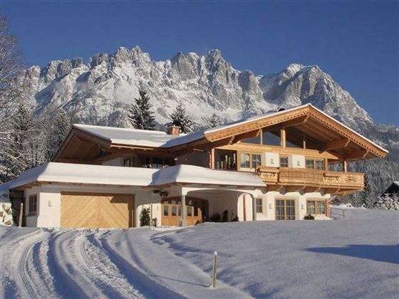 A beautiful, modern chalet in the snow, surrounded by majestic mountains. The calm winter landscape radiates coziness.
