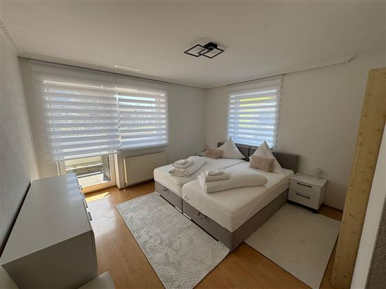 A modern bedroom with two single beds and bright curtains. The clean furnishings create an inviting atmosphere.